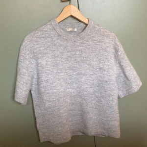Jätte snygg ljusgrå stickad tröja med kort ärm - Supermjuk ljusgrå stickad tröja från Gina tricot med korta ärmar och rund halsringning. Perfekt för lager-på-lager och enkel att styla till olika outfits. Ribbstickade kanter vid ärmslut och nederkant.