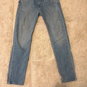 Levis 502 ljusblå jeans - Ljusblå Levis 502 jeans med klassisk femficksdesign och rakt snitt. Jeansen har en normal passform och är tillverkade i denim. Perfekta för dig som gillar en tidlös och avslappnad stil. Levis-logga på bakfickan och patch i midjan.