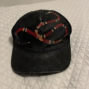 Svart keps med ormtryck från Gucci - Den är äkta säljs ej längre ganska sleten men den kan även gå upp i pris. 