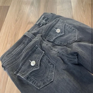 Grå bootcut jeans från True Religion - Säljer ett par grå jeans från True Religion med bootcut-passform. Strl 25 och mid waist. Byte är ockås ok! 