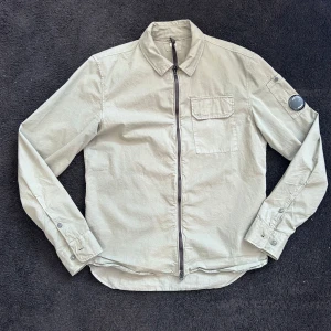 Grön skjorta med dragkedja från C.P. Company - Säljer nu min gröna C.P. Company overshirt i st S. Använd fåtal gånger och är 10/10 skick. 