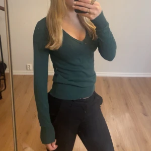 Grön v-ringad tröja från Cubus - Mörkgrön v-ringad tröja från Cubus i mjuk bomullsblandning. Tröjan har lång ärm och en figurnära passform som sitter snyggt. Skönt material och lagom varm, säljer för att den inte kommer till användning!💗