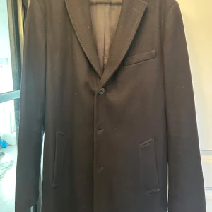 Svart ytterrock från J.Lindeberg - Säljer en klassisk svart rock från J.Lindeberg med smal passform. Kavajen har tre knappar framtill, två fickor med lock och en bröstficka. Perfekt för bal eller fest.