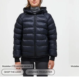 Svart dunjacka från Peak Performance - Säljer en mörkblå pufferjacka från Peak Performance med huva och dragkedja framtill. Jackan är vadderad och har lång ärm samt ribbade muddar. Perfekt för kyliga dagar och har en klassisk, sportig look.