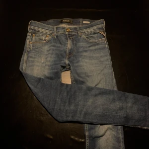 Blå Replay jeansbyxor herr - Säljer ett par klassiska blå jeans från Replay i modell Jondrill. Byxorna har slim passform, fem fickor och snygga slitningar. Midjan är w29 och längden L 32. 