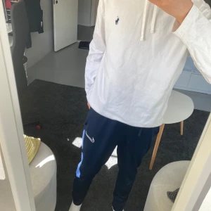 Vit hoodie från Polo Ralph Lauren - Säljer en klassisk vit hoodie från Polo Ralph Lauren med liten broderad logga på bröstet. Tröjan har långa ärmar, huva med dragsko och är tillverkad i mjuk bomull. Perfekt för en avslappnad och stilren look. Inte använd.