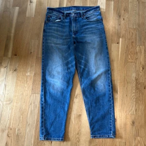 Levi's 550 blå jeans - Klassiska blå Levi's 550 jeans med raka ben och femficksmodell. Jeansen har normal passform och är tillverkade i bomull. Snygg tvätt med lätt slitning framtill och bakfickor med den ikoniska Levi's-lappen bak i midjan. Gott skick o strl w34 l32