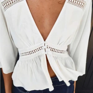 Vit blus från Zara - Säljer en vit blus från Zara med djup v-ringning och knyt framtill. Blusen har trekvartsärm.