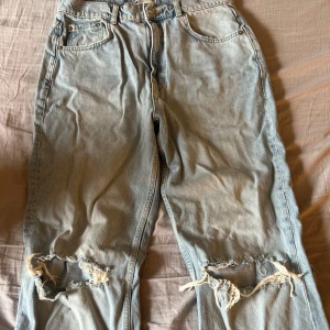 Ljusblå slitna jeans från Gina tricot  - Ljusblå jeans med rejält slitna knän och klassisk femficksmodell. Raka ben och normal passform. Perfekta för en avslappnad och trendig look.