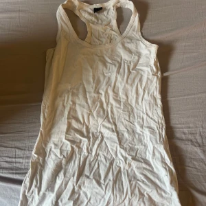 Vit linnetopp från Gina Tricot - Säljer en klassisk vit linnetopp från Gina Tricot. Modellen är ärmlös med brottarrygg och tillverkad i mjuk bomull. Perfekt till varma dagar eller som lager under andra plagg.