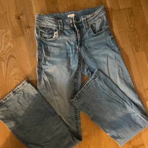 Ljusblå bootcut jeans från Gina  - Säljer ett par ljusblå jeans med bootcut-modell. Jeansen har klassisk femficksdesign, knapp och dragkedja framtill samt lätt slitna detaljer vid fickorna. Perfekta för dig som gillar en avslappnad och tidlös stil.