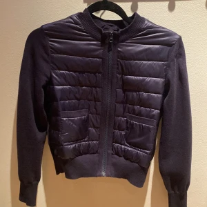 Mörkblå cardigan jacka från Gina Tricot - Säljer en svart cardigan jacka från Gina Tricot med quiltade partier framtill och två fickor. Jackan har dragkedja och ribbade muddar vid ärmslut och nederkant. Perfekt för lager-på-lager under hösten eller våren. Köpte för 400 hundra, kom med prisförslag! Anvönt typ 2 ggr, skriv om ni har nå frågor!