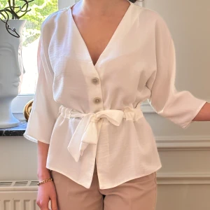 Vit trekvartsärm blus m knytning framtill  - Vit trekvartsärm blus m knytning framtill  och knappar från Primark. Mycket sparsamt använd. Blusen är i 34 men passar även som 32 (personen i bilden är ca 1.60 m och har XXS i storlek). 