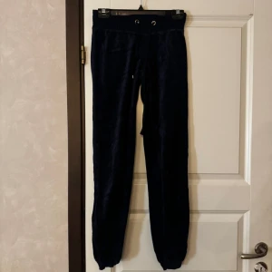 Mörkblåa mjukisbyxor med dragsko - Mysiga mörkblåa mjukisbyxor med resår och dragsko i midjan. Byxorna har en smal passform och är perfekta för avslappnade dagar. Mjukt material som känns skönt mot huden.