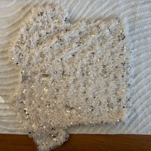 Beige fluffig paljettopp från ZARA - Superfin beige topp från ZARA med fluffigt material och massor av glittriga paljetter. Perfekt för dig som vill sticka ut! Toppen har en croppad passform och är ärmlös. Säljes då den inte kommer till användning längre.