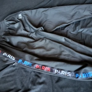 PSG fotbollströja i röd och blå och PSG Byxor - Säljer en PSG fotbollströja från Nike med Qatar Airways-tryck. Tröjan har korta ärmar och är i en snygg färgövergång från röd upptill till blå nedtill. Även ett par byxor med.   Tröja 250kr.                                                 Byxor 150kr.                                                          Båda 300kr