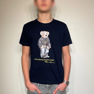 Svart t-shirt från Ralph Lauren - Snygg svart t-shirt från Ralph Lauren med det ikoniska Polo Bear-trycket på framsidan. Tshirten har en normal passform och är kortärmad. Perfekt inför våren och sommaren som snart kommer 🏖️Helt nytt skick. Priset går absolut att diskuteras. Skriv gärna om ni har frågor eller funderingar! 💬