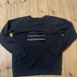 Svart sweatshirt från Peak Performance - Säljer en svart sweatshirt från Peak Performance med tryckt logotyp i olika nyanser på bröstet. Tröjan har långa ärmar och rund halsringning. Perfekt för en avslappnad stil. Pris kan diskuteras 