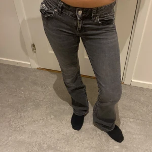 Grå jeansbyxor - Snygga grå jeansbyxor med låg midja och bootcut-stil. Byxorna har klassiska femficksdetaljer och en knappgylf. Perfekta för en avslappnad look.