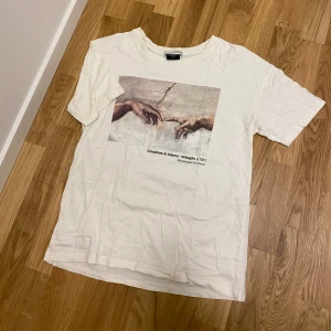 t-shirt med konsttryck från Pull&Bear - Creme vit t-shirt från Pull&Bear med ett konstnärligt tryck av Michelangelos 'Skapelsen av Adam'.