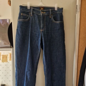 Blå jeans från Lee - Ett par blåa jeans från Lee i modellen Jane. Använda ett fåtal gånger, men har fått en liten reva i tyget nere vid ena benet. Rak passform med medel/hög midja. 