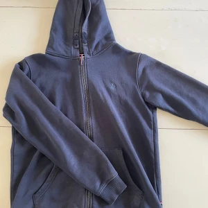 Mörkblå polo hoodie - Säljer en mörkblå hoodie från U.S. Polo Assn. med dragkedja och huva. U.S polo assn har nästan ett identiskt märke som Ralph lauren fast mycket mer prisvärt. Tröjan är i bra skick och är i storlek 15-16 men passar alla upp till 180cm. Fritt fram att ställa frågor och be om någon mer bild och om priset är dåligt så kom med ett förlag men INGA SKAMBUD! Mvh Viggo 