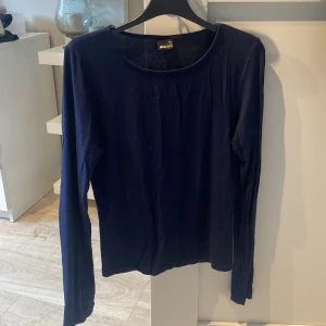 Mörkblå långärmad topp från Gina Tricot - Säljer en stilren mörkblå långärmad topp från Gina Tricot. Perfekt för en enkel och snygg look. Tillverkad i ett mjukt material som känns skönt mot huden.