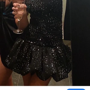 Maje svart paljettklänning - Säljer nu min så snygga SLUTSÅLDA maje klänning med paljetter och volangdetaljer. Klänningen har axelbandslös design som ger en elegant look och gör den perfekt för nyår eller andra firanden💫Klänningen är i mycket gott skick förutom en söm på insidan av klänningen som gått upp, syns inte och går att sy ihop✨ 