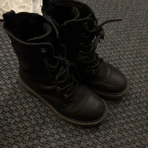 Svarta boots med snörning - Säljer ett par svarta boots med snörning och robust sula. Perfekta för höst och vinter med en stilren design. De har en högre skaft och är gjorda i skinnliknande material.