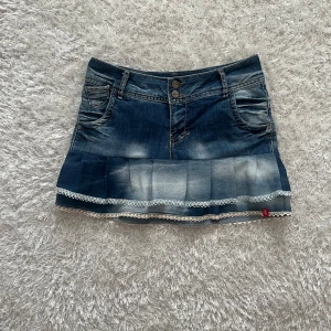 Jeanskjol med spetsdetaljer - Lågmidjad jeanskjol omsydd från ett par jeans. Midjemått tvärsöver- ca 40cm Längd- ca 36cm
