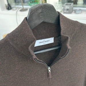 Brun halfzip från Gran Sasso - Säljer en elegant brun tröja från Gran Sasso. Tröjan har en dragkedja vid halsen och långa ärmar, perfekt för kyligare dagar. Den är tillverkad i Italien och erbjuder både stil och komfort.