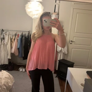 Rosa ärmlös topp - Säljer en söt rosa ärmlös topp med halterneck-design. Toppen har en lös passform och är tillverkad i ett lätt och luftigt material, perfekt för varma dagar. En fin rosa färg och ett supernajs material/ detaljer i tyget❤️