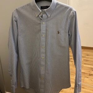 Randig skjorta från Polo Ralph Lauren-Aldrig andvänd  - Säljer en stilren blå- och vitrandig skjorta från Polo Ralph Lauren-Aldrig andvänd!Perfekt för en klassisk look. Ny pris 1600