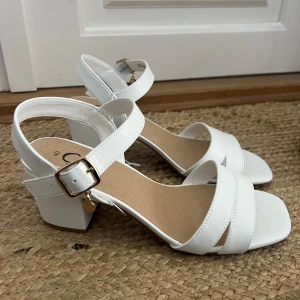 Vita sandaler med klack och spänne - Snygga vita sandaler med klack och justerbart spänne. Aldrig använda med snöret kvar emellan! 💞