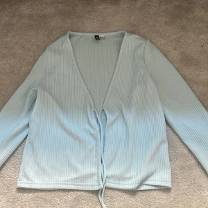 Ljusblå ribbad kofta - Säljer en ljusblå ribbad kofta med knyt framtill. Från h&m. Koftan har en v-ringad design och långa ärmar, perfekt för en stilren look. Passar bra till både jeans och kjol. 💙