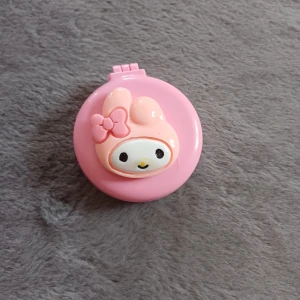 Rosa hopfällbar borste med spegel - Söt rosa hopfällbar borste med spegel och en karaktär med rosett på framsidan. Perfekt för att ha med i väskan för snabba touch-ups. Borsten har svarta piggar med rosa toppar.