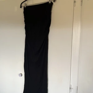 Svart långkjol  - Säljer en elegant svart långkjol med en stilren design. Lite åtdragande detaljer för att få fram former och siluett. Framhäver kroppen väldigt fint. 
