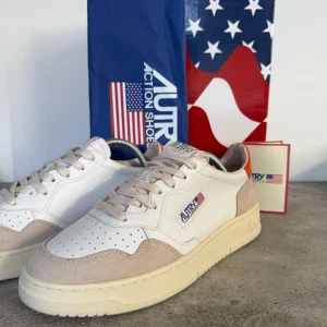 Sneakers från Autry - Snygga sneakers från Autry i vitt och beige med orange detaljer. Skorna har en klassisk design med snörning och perforerade detaljer på ovansidan. Tillverkade i en kombination av skinn och mocka för en stilren look. Aldrig använda med box och dustbag. NYPRIS 1999kr mitt pris 900kr