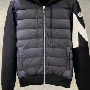 Svart pufferjacka med huva - Snygg svart pufferjacka från Moncler med dragkedja och huva. Jackan har långa ärmar och ett stort vitt 'M' på ena ärmen. Perfekt för kyligare dagar.