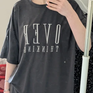 Svart t-shirt med text - Snygg svart t-shirt med texten 'OVER THINKING' i vitt. Perfekt för en avslappnad stil. T-shirten har en oversized passform och korta ärmar.