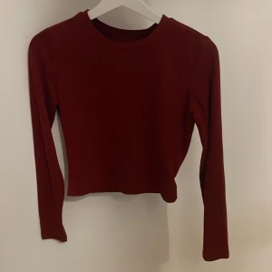 Röd långärmad croppad topp - Snygg röd croppad topp med långa ärmar. Perfekt för en trendig look. Enkel design som passar till många olika outfits.