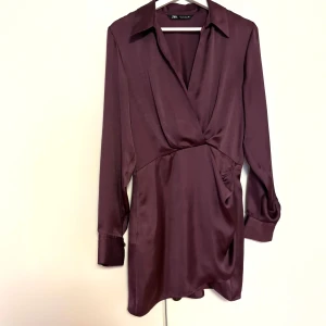 Vinröd omlottklänning från Zara - Snygg vinröd/lila omlottklänning från Zara i ett glansigt material. ❣️