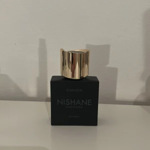 Karagoz Extrait de Parfum från Nishane - Elegant parfymflaska från Nishane med namnet Karagoz. Flaskan är svart med en lyxig guldfärgad kork. Perfekt för den som söker en sofistikerad doftupplevelse. 