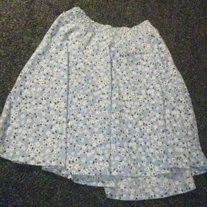 Blommig kjol - Söt blommig kjol i ljusblått från lager 157. Kjolen har ett elastiskt midjeband för bekväm passform och ett härligt blommönster i vitt och svart💞