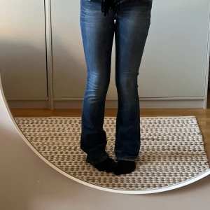 Blå bootcut jeans från Crocker - Snygga blå bootcut jeans från Crocker med klassisk femficksdesign. Jeansen har en bekväm passform och är perfekta för en avslappnad stil. De är tillverkade i slitstarkt denim och har en traditionell knappgylf.