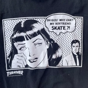 Svart t-shirt från Thrasher - Säljer en svart t-shirt från Thrasher med ett coolt serietidningstryck på framsidan. Perfekt för dig som gillar streetwear och skatekultur. T-shirten har korta ärmar och en rund halsringning.