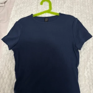 Mörkblå ribbad topp från Shein - Säljer en mörkblå ribbad topp från Shein. Toppen har en enkel design med korta ärmar och rund halsringning. Perfekt för en avslappnad stil.