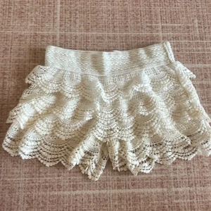 Vita spets shorts - Shortsen jag visar på bilden är andvänder men dom som jag kommer skicka kommer vara i helt nytt skick . Kommer att skicka varan när jag kommer hem den 5 april så köp inte än utan skicka till mig via intresse . Säljer ett par vita shorts med vacker spetsdesign. De har  flera lager av spets som ger en fin volangeffekt. Perfekta för sommarens varma dagar!