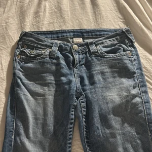 Blå bootcut jeans från True Religion - Snygga blå bootcut jeans från True Religion med slitningar på låren! Bra skick och inte använda så mycket. Passar mig som är runt 160. 