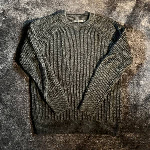 Mörkgrå stickad tröja med rund hals - Tröjan är S men passar bra till både S och M.                      Säljer en mörkgrå stickad tröja från H&M med grov ribbad struktur och rund hals. Tröjan har långärmade raglanärmar och sitter snyggt med en normal passform. Perfekt för dig som gillar enkel och stilren look.